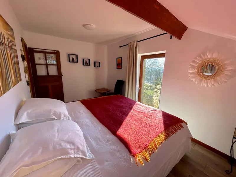 Bedroom 3 with a red throw on the bed and sunburst mirror
