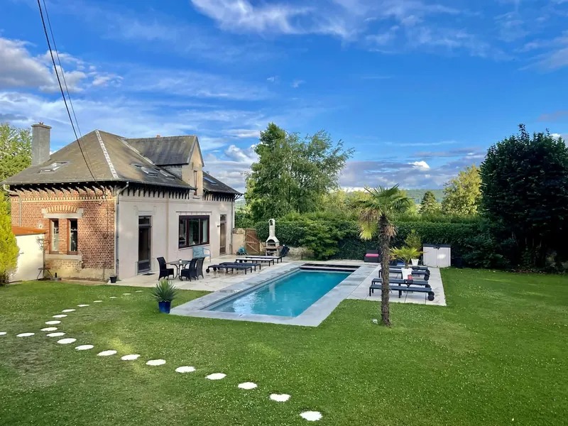 The poolhouse garden by day: lawn, stepping stones and the pool in the sun