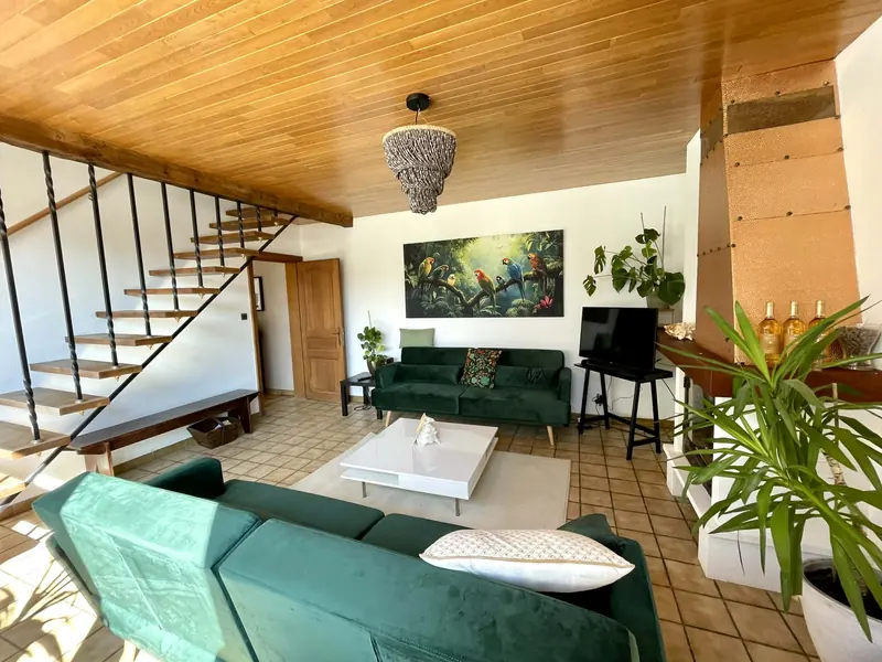 Living room with green velvet sofas, plants and a colourful jungle painting