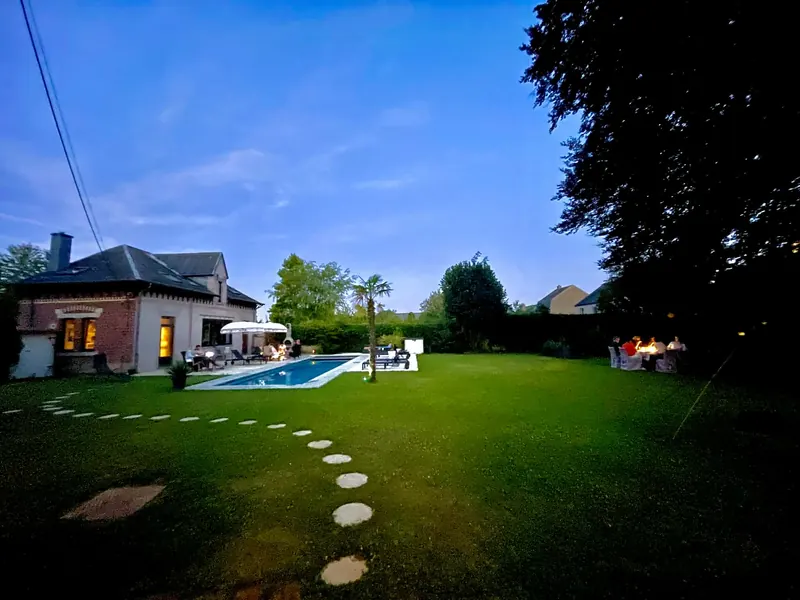 The same garden in the evening with the pool lit up in turquoise