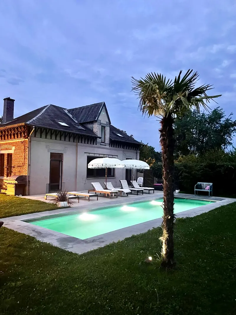 The poolhouse at dusk with the pool lights on
