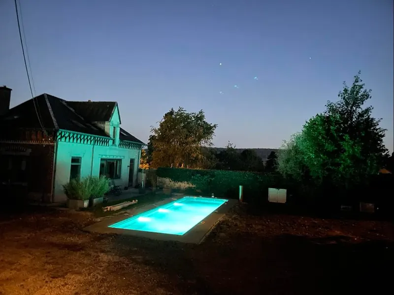 The illuminated pool in the evening in front of the poolhouse